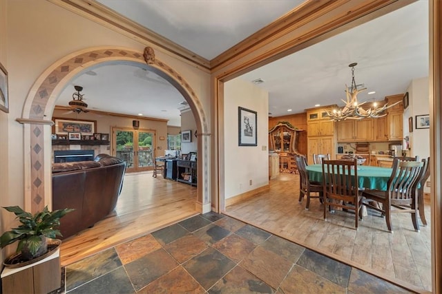 dining area featuring ornamental molding, ceiling fan with notable chandelier, and dark wood-type flooring