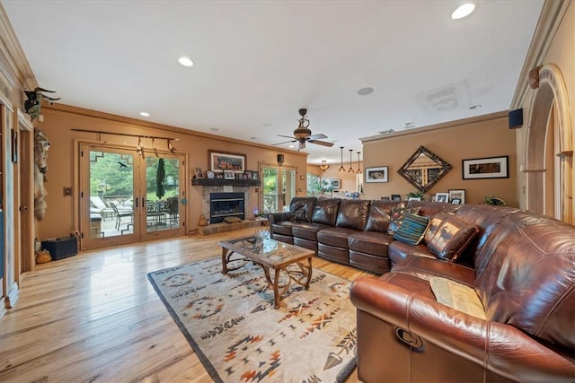 living room with ceiling fan, a fireplace, light wood-type flooring, and ornamental molding