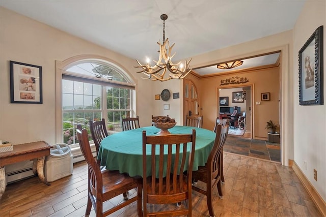 dining area featuring a chandelier, hardwood / wood-style flooring, baseboard heating, and crown molding