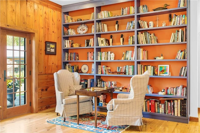 sitting room with light hardwood / wood-style flooring and wood walls