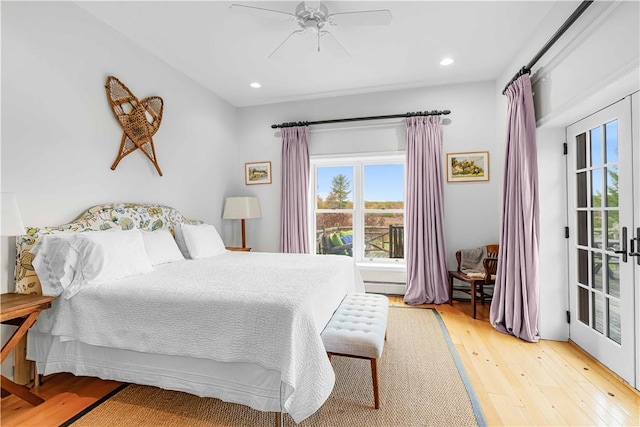 bedroom with ceiling fan, light hardwood / wood-style floors, a baseboard heating unit, and french doors