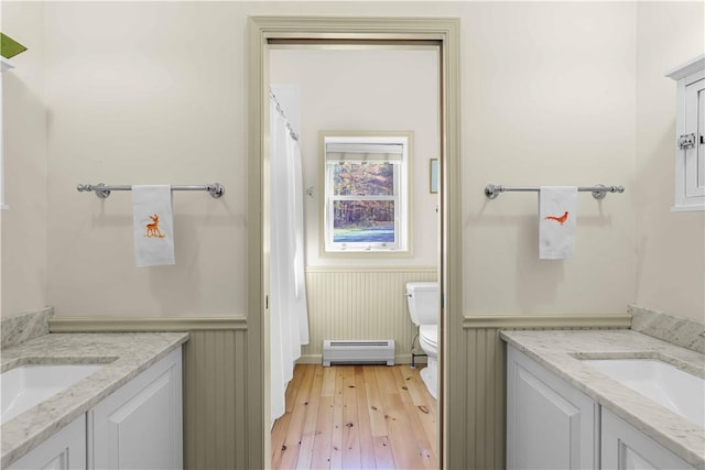 bathroom with hardwood / wood-style floors, vanity, a baseboard radiator, and toilet