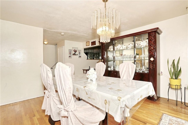 dining space with light hardwood / wood-style floors and an inviting chandelier