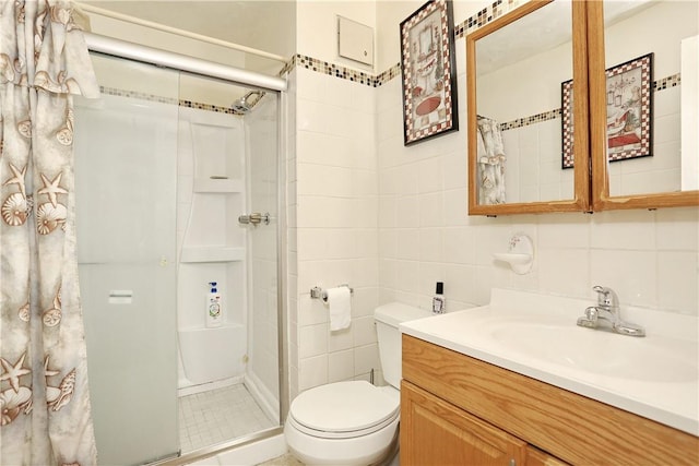 bathroom featuring vanity, toilet, a shower with shower door, and tile walls