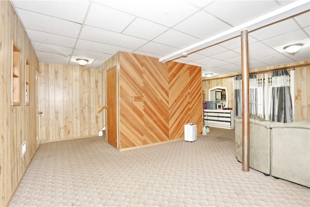 basement featuring a drop ceiling, wood walls, and carpet floors