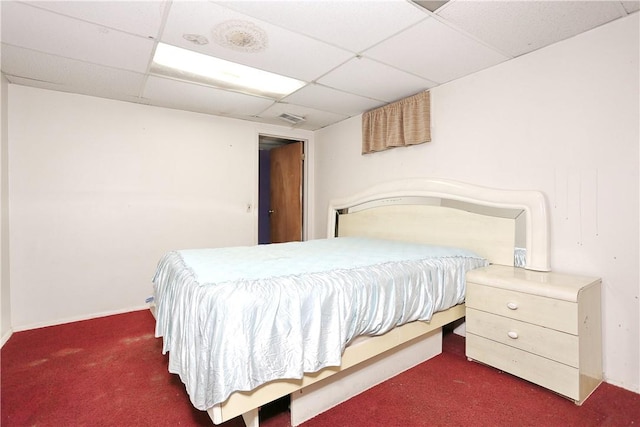 bedroom with dark colored carpet and a drop ceiling