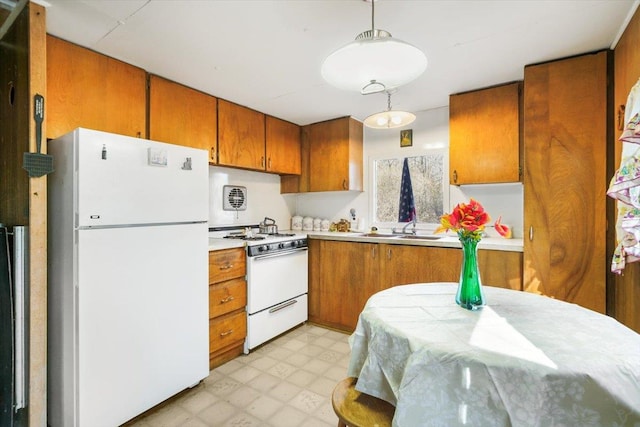 kitchen with sink, white appliances, and hanging light fixtures