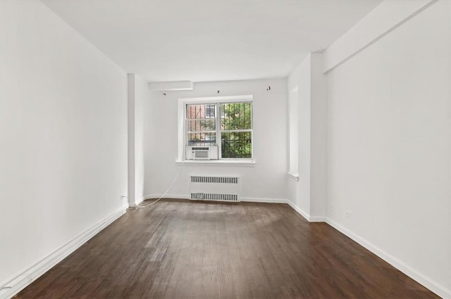 spare room featuring cooling unit, radiator heating unit, and dark wood-type flooring