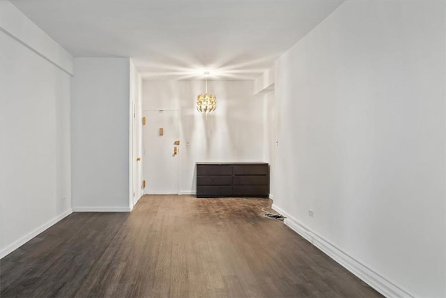 empty room featuring dark hardwood / wood-style flooring and a notable chandelier