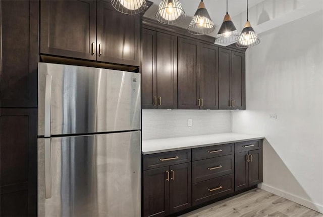 kitchen featuring pendant lighting, stainless steel fridge, dark brown cabinetry, and light hardwood / wood-style flooring