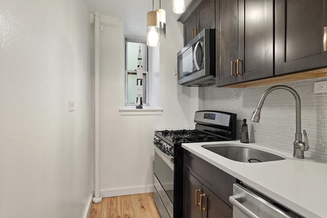 kitchen featuring decorative backsplash, dark brown cabinets, stainless steel appliances, light hardwood / wood-style floors, and hanging light fixtures