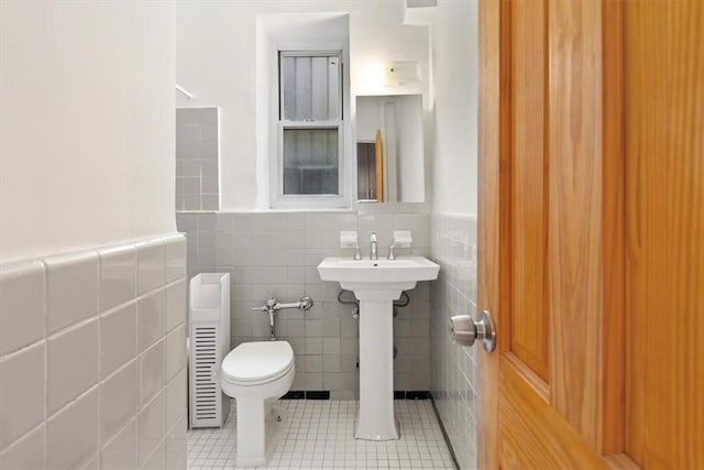 bathroom featuring tile patterned flooring, toilet, and tile walls