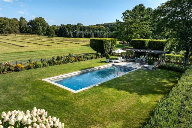 view of swimming pool with a pergola, a patio area, a yard, and a rural view