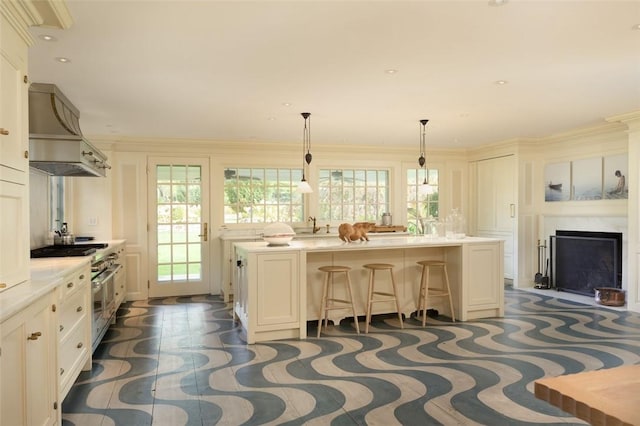 kitchen featuring wall chimney exhaust hood, a kitchen island, a kitchen breakfast bar, and crown molding