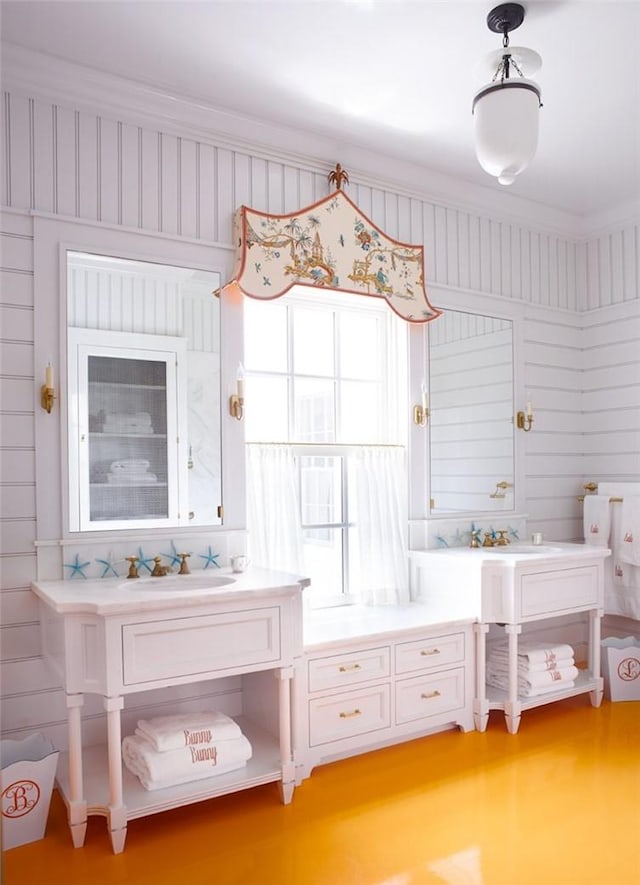 bathroom featuring crown molding, sink, and wooden walls