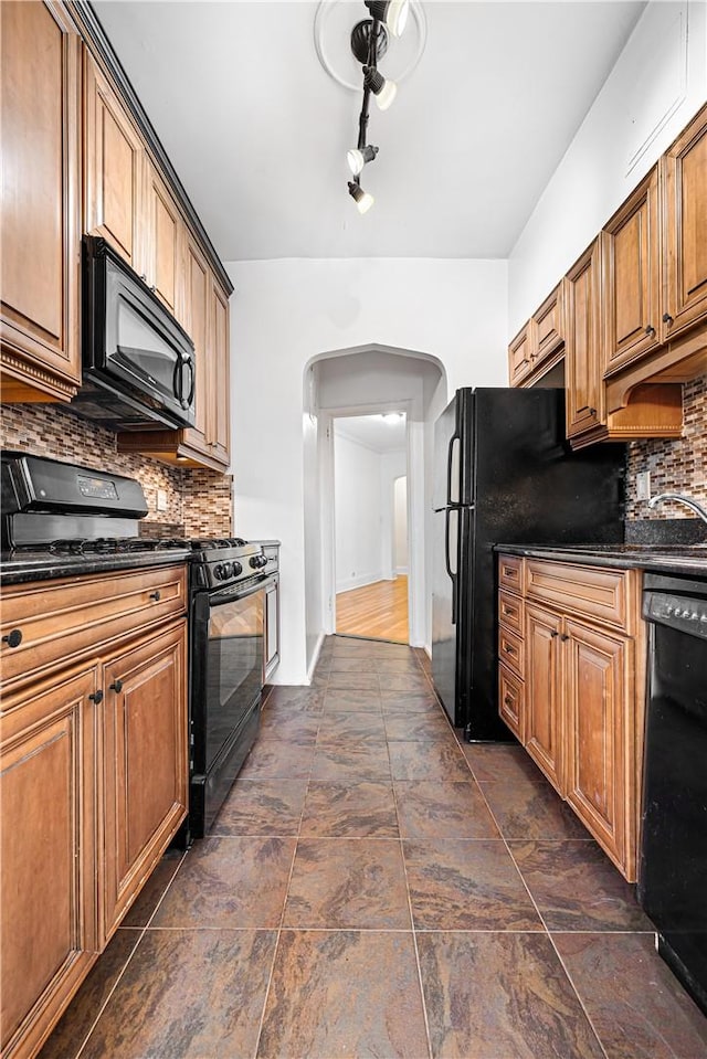 kitchen with backsplash, dark stone counters, and black appliances