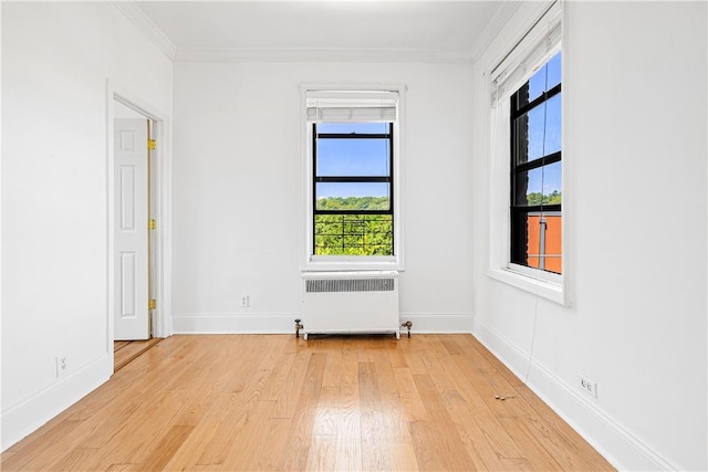 spare room with light hardwood / wood-style flooring, radiator, and ornamental molding