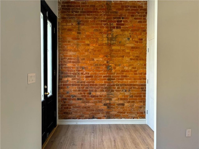 interior space featuring wood-type flooring and brick wall