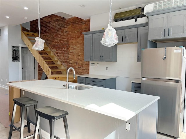 kitchen featuring stainless steel fridge, sink, a kitchen island with sink, and light hardwood / wood-style floors