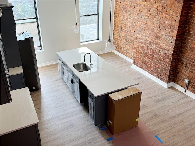 kitchen with sink, a healthy amount of sunlight, brick wall, and light wood-type flooring