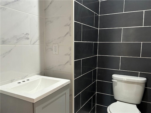 bathroom with vanity, toilet, and tile walls