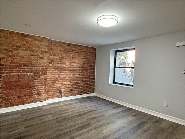 empty room with dark hardwood / wood-style floors and brick wall