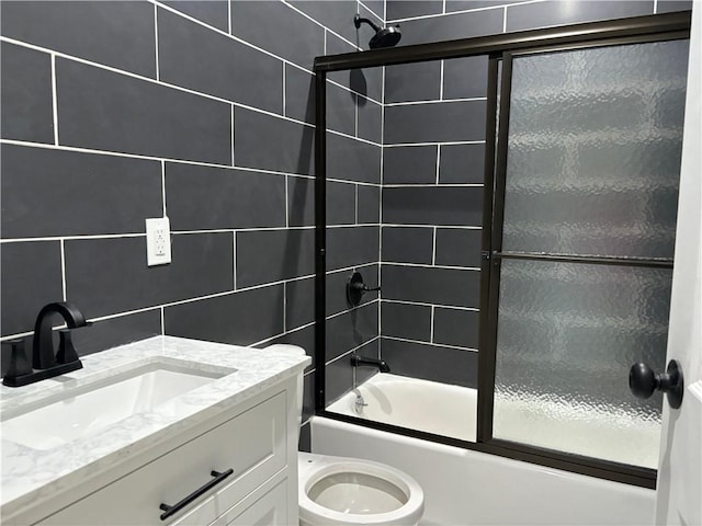 full bathroom with toilet, vanity, tile walls, and combined bath / shower with glass door