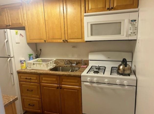 kitchen with stone counters, sink, and white appliances