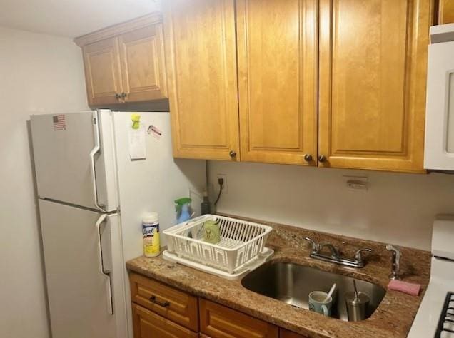 kitchen with white appliances, sink, and stone counters