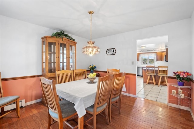 dining space featuring light wood-type flooring, an inviting chandelier, and baseboard heating