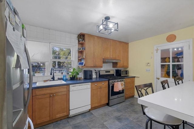 kitchen featuring decorative backsplash, stainless steel appliances, a chandelier, and sink