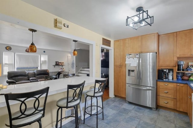 kitchen featuring a breakfast bar area, hanging light fixtures, and stainless steel refrigerator with ice dispenser