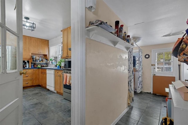 kitchen with white dishwasher, stainless steel range oven, sink, and light brown cabinetry