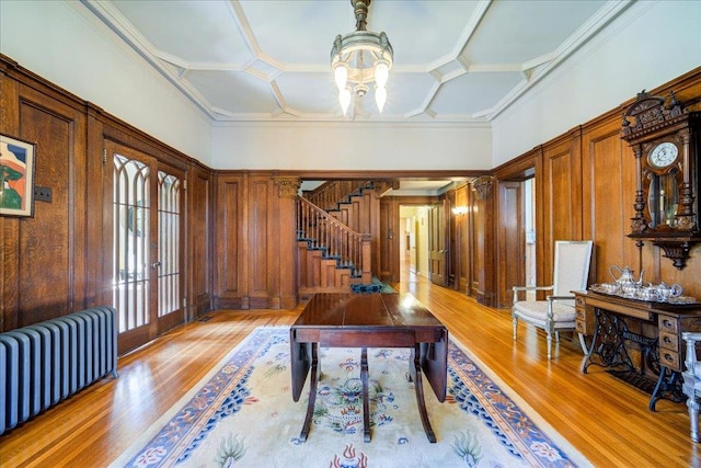 home office with wooden walls, radiator heating unit, and light hardwood / wood-style flooring