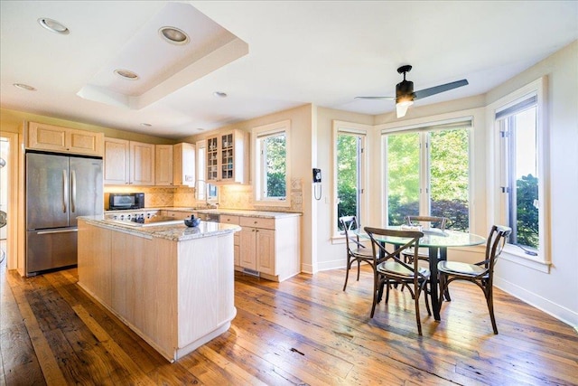 kitchen featuring stainless steel refrigerator, ceiling fan, wood-type flooring, light brown cabinetry, and a kitchen island