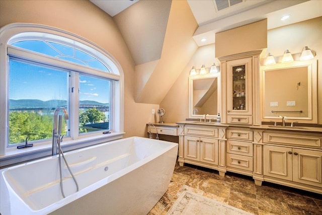 bathroom featuring a mountain view, lofted ceiling, a tub, and vanity