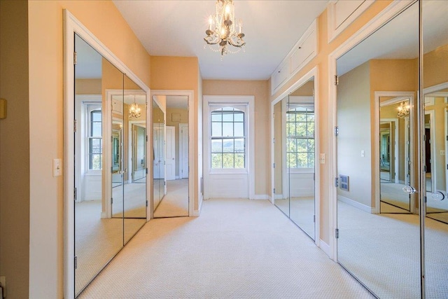 doorway to outside featuring light carpet and an inviting chandelier