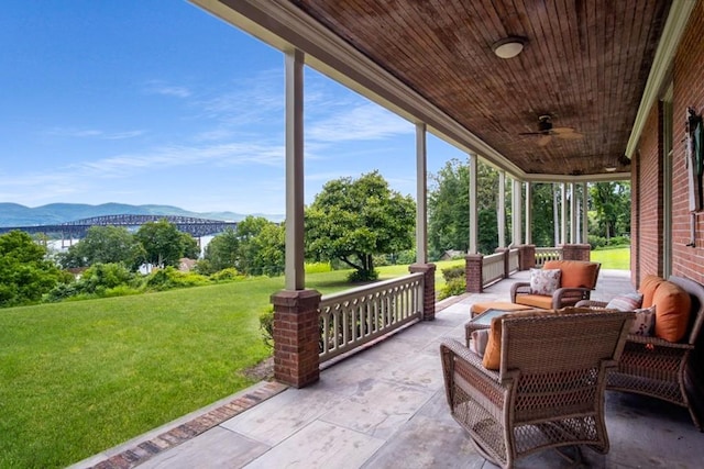 sunroom with a mountain view, ceiling fan, and wood ceiling