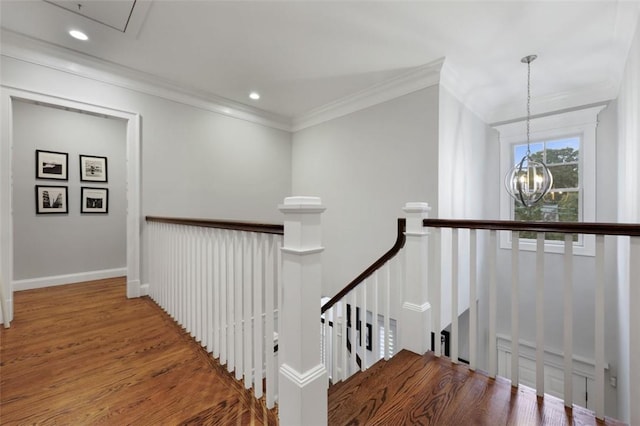 stairway featuring hardwood / wood-style floors, ornamental molding, and a notable chandelier