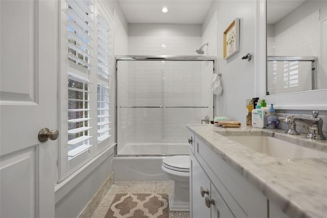 full bathroom with vanity, bath / shower combo with glass door, and toilet