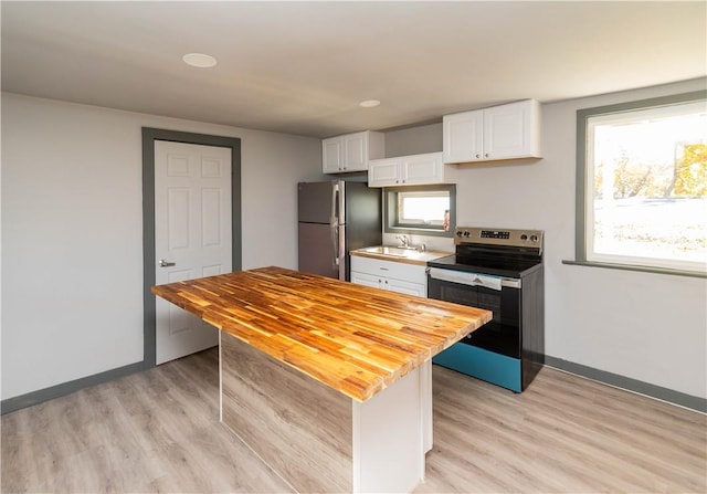 kitchen with light hardwood / wood-style flooring, white cabinets, a healthy amount of sunlight, and appliances with stainless steel finishes