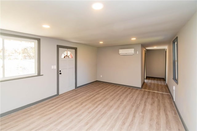 interior space with light hardwood / wood-style floors and a wall unit AC