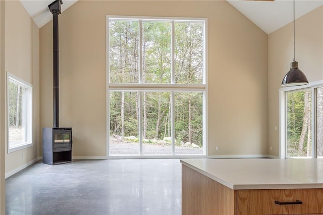 unfurnished living room featuring plenty of natural light, a wood stove, and high vaulted ceiling