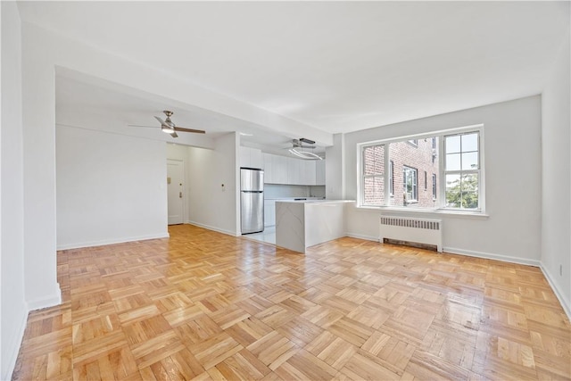 unfurnished living room featuring radiator heating unit and light parquet flooring