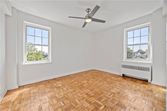 empty room with ceiling fan, radiator heating unit, and light parquet flooring