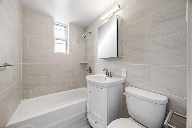 full bathroom featuring toilet, vanity, tiled shower / bath combo, and tile walls