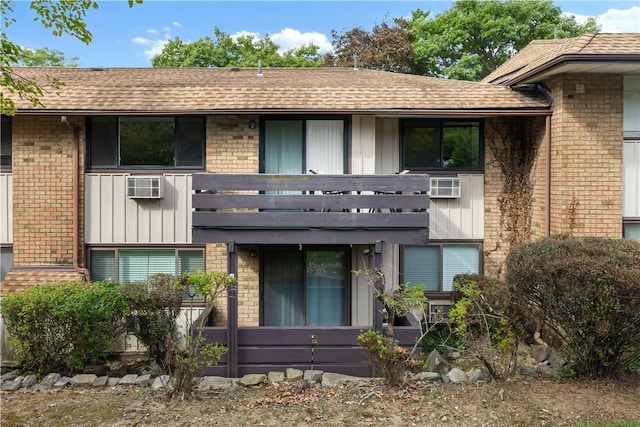 rear view of property with a balcony and a wall unit AC