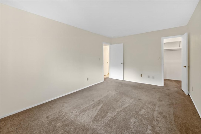 unfurnished bedroom featuring carpet flooring and a spacious closet