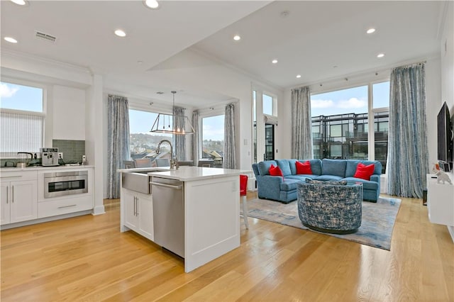 kitchen with a kitchen island with sink, white cabinets, sink, appliances with stainless steel finishes, and plenty of natural light