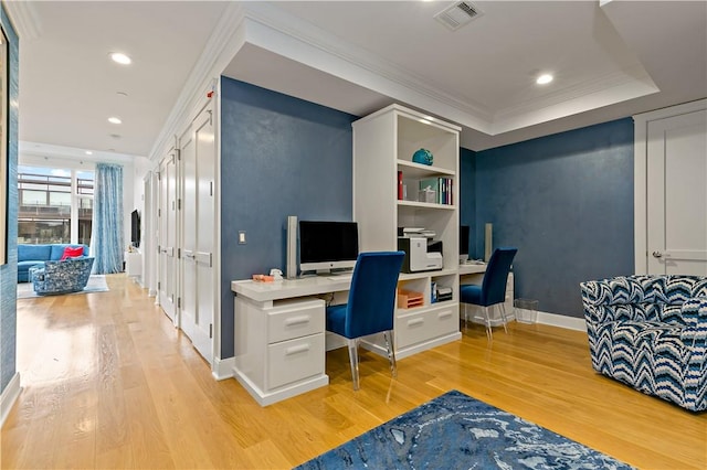 office space with a raised ceiling, crown molding, and light hardwood / wood-style flooring